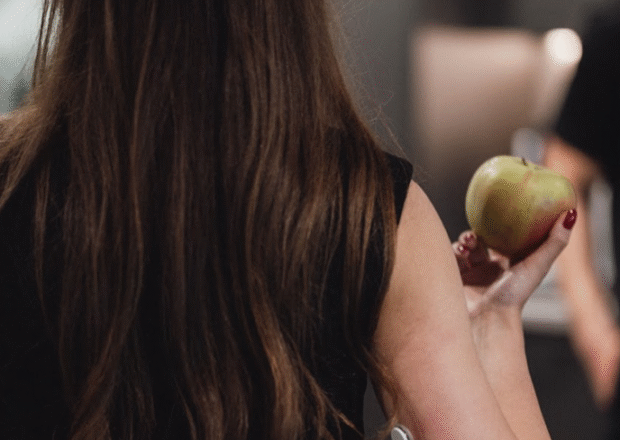 Sieviete ēd ābolu ar CGM uz rokas